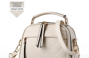 Detailed close-up of creamy-white pebbled leather bag with V-shaped stitching and gold zipper