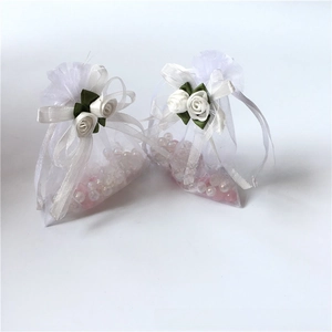 Detailed view of white organza drawstring pouch with silk rose and satin ribbon bow decoration