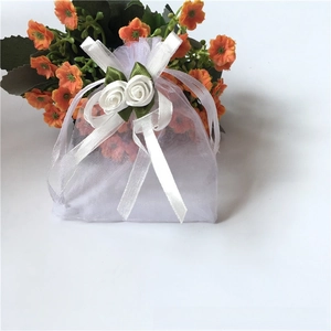 Detailed view of white organza gift bag with satin rose decorations and drawstring