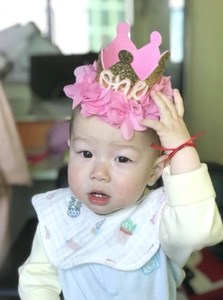 Detailed view of pink mesh flower headband with golden glitter crown and one lettering