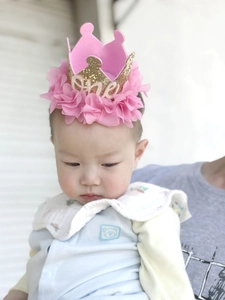 Close-up of baby girl wearing pink floral gold glitter crown headband for first birthday