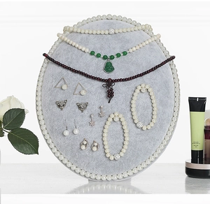 Detail of oval gray velvet jewelry stand showcasing pearl necklaces and earrings