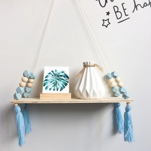 Macro detail of Nordic hanging wood shelf with macaron beads and light blue tassels