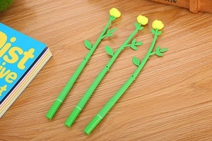 Three creative yellow flower shaped pens laying on a wooden desk next to a blue book