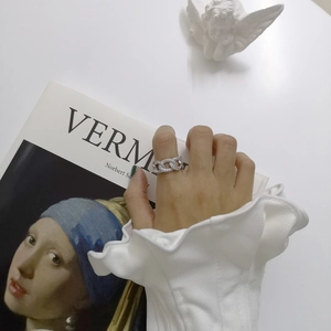 Artistic detail of silver interlocking chain ring with zircons worn by model