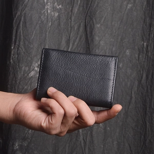 Close-up of black lychee grain leather wallet held in hand showing detailed texture