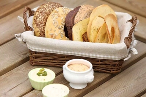 Artisan woven basket with assorted fresh breads and spreads on a rustic wooden table