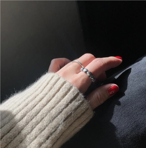 Detail view of minimalist silver rings with faceted texture on a model's hand