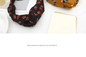 Close-up of knotted fabric headbands in black floral and ginger yellow patterns