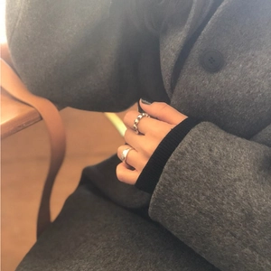 Close-up of a person wearing minimalist 925 sterling silver rings on a wooden background