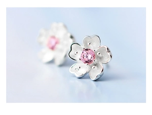 Macro view of cherry blossom earrings with silver petals and a pink zircon center