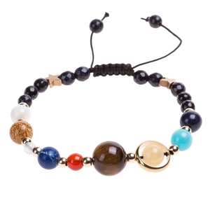 Detail of solar system bracelet with natural stones and gold stars on black woven cord