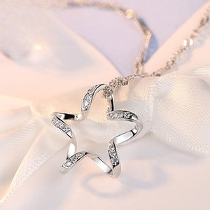 Close-up of S925 sterling silver hollow star pendant with zircon stones on white silk