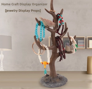 Detail of tree branch jewelry stand with bird accents holding necklaces and rings