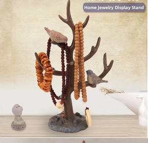 Detail of tree branch jewelry stand with decorative bird and rustic wood grain texture