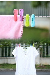 Detail of colorful plastic clothespins clipping clothes on a fence for windproof drying
