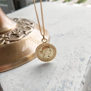 Detailed macro view of gold coin pendant with Elizabeth II portrait and fine chain