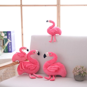 Set of four cute pink flamingo plush toys in various sizes on a cozy beige sofa