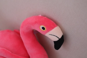 Detailed close-up of flamingo plush head with fine embroidery eyes and black-white beak