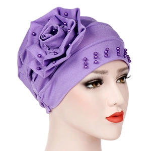 Close-up of purple turban hat with elegant beaded flower detail and pearls