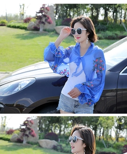 Blue chiffon beach shawl with red floral embroidery shown on a model outdoors