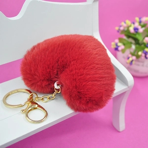Llavero de corazón de felpa roja con anillo dorado en un mini banco blanco