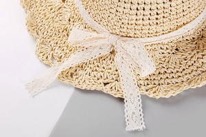 Détail d'un chapeau de paille pour femme avec nœud en dentelle et bordure festonnée