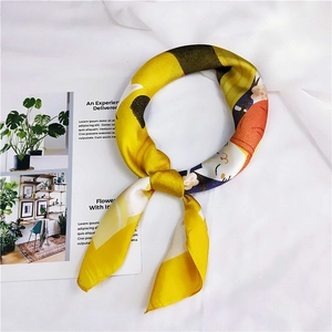 Detailed view of silk-like scarf featuring yellow cat print and cherry blossom patterns