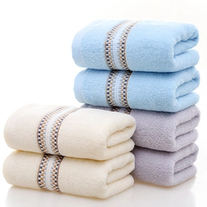 Détail de serviettes en coton empilées montrant la texture ondulée et la bordure jacquard