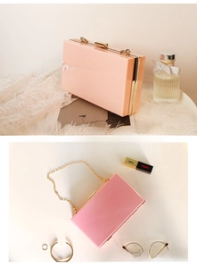 Detail of pink acrylic evening clutch bag with gold metal frame and detachable chain