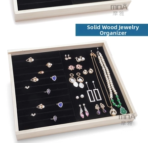 Detail of wooden jewelry tray with black velvet ring slots and necklace display section
