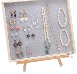 Close-up of pearl necklaces and various earrings on a grey velvet jewelry display tray