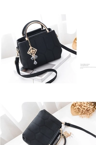 Details der schwarzen Handtasche mit Sechseck-Prägung und goldenem Rundgriff