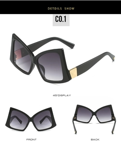 Detail view of oversized bow-shaped sunglasses with black frames and golden metal accents