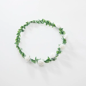Detailed view of six white foam roses and green leaves on a floral headband crown