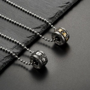Retro stainless steel lotus mantra cylinder pendants on stone textured background