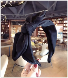 Detail of oversized black bow headband in matte satin fabric for a sweet elegant style