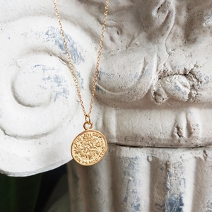 Detailed close-up of 1953 sixpence coin pendant in gold finish on stone base