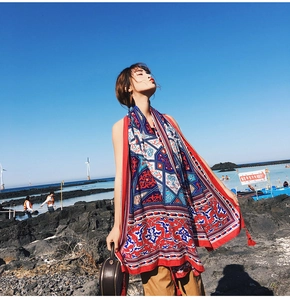 Detail of bohemian red and blue shawl with fringe on beach rocks for summer sun protection