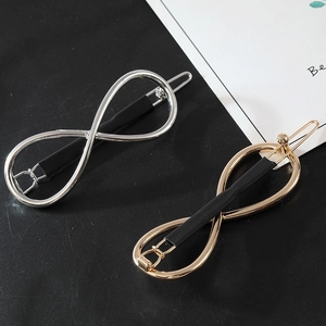 Detail of gold and silver infinity symbol hair clips with black non-slip grip elements