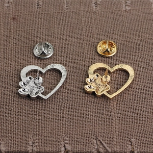 Macro detail of gold and silver heart brooch backs showing the metal butterfly clasp fasteners