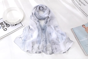 Detailed view of lightweight silk scarf with blue leaf print on a white base