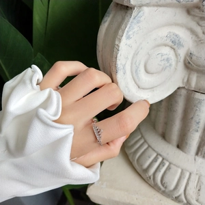 Detailed close-up of a silver crown ring with sparkling zircons on a model's hand