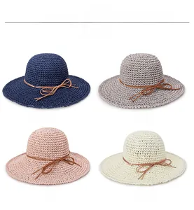 Detail of hand-woven straw sun hats in blue, grey, pink, and beige with bow knots