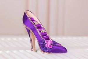 Macro view of purple satin high heel ring holder with gold trim and ribbon bow