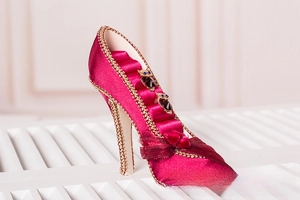Detail of high heel ring holder with red satin fabric, gold beads and five storage slots