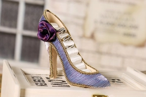 Detail of high heel ring holder with purple fabric, gold beads, and satin rose