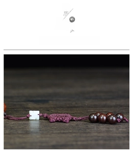 Macro shot of dark wood beads with purple braided cord and a white jade-like accent