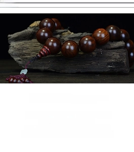 Macro shot of polished red rosewood beads with deep wood grain and silk tassel detail