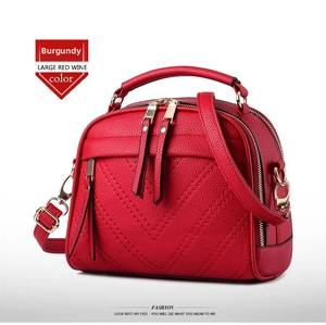 Detail of wine red crossbody bag with litchi grain leather and V-shaped stitching